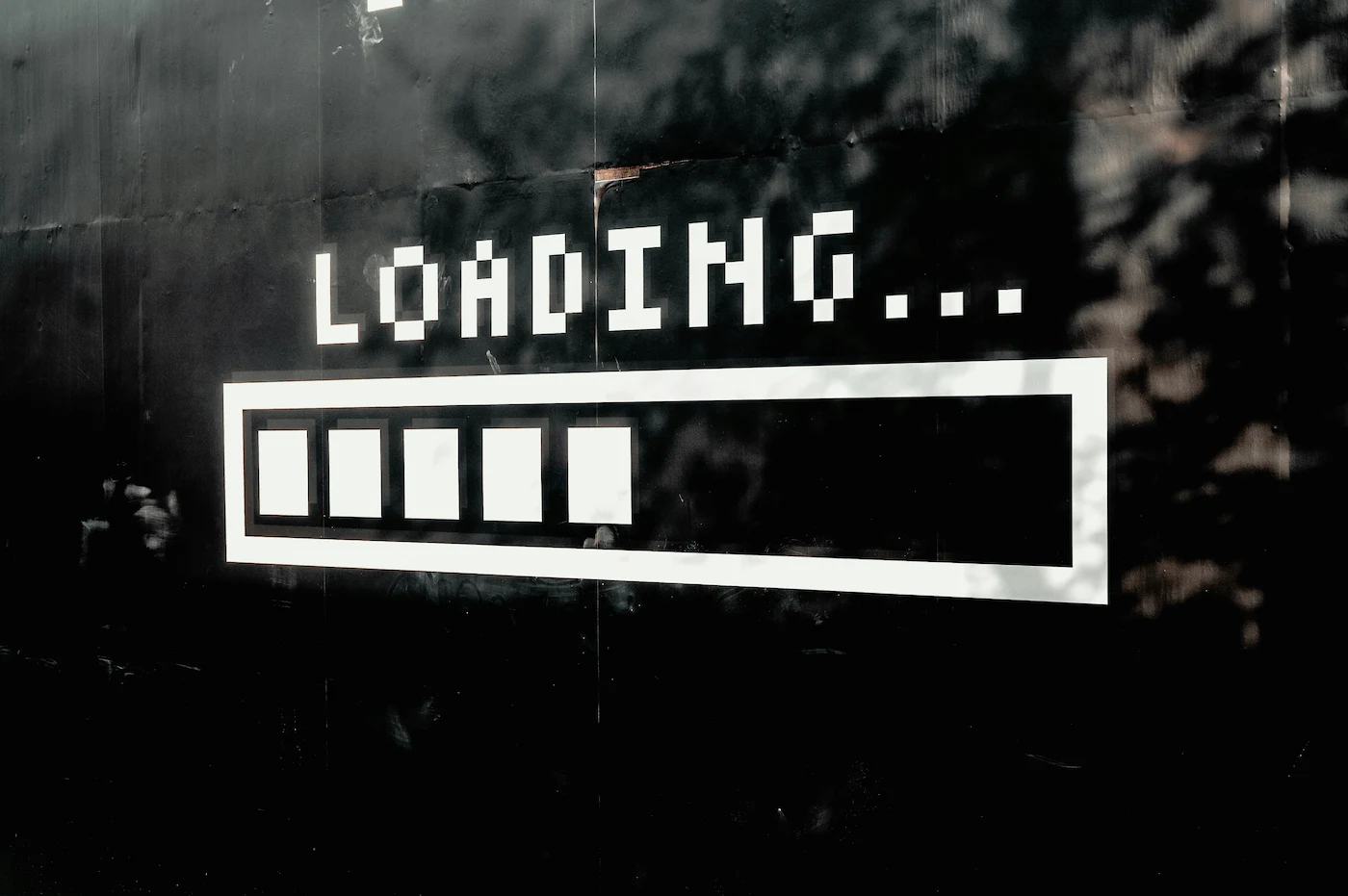 A digital 'LOADING...' bar with four white rectangular blocks progressing on a black background, suggesting data processing or a waiting state.
